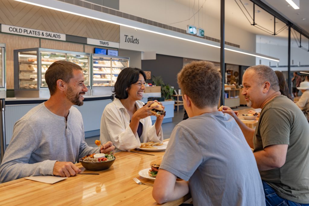 four friends smiling and enjoying a burger and salad in the port arthur cafe